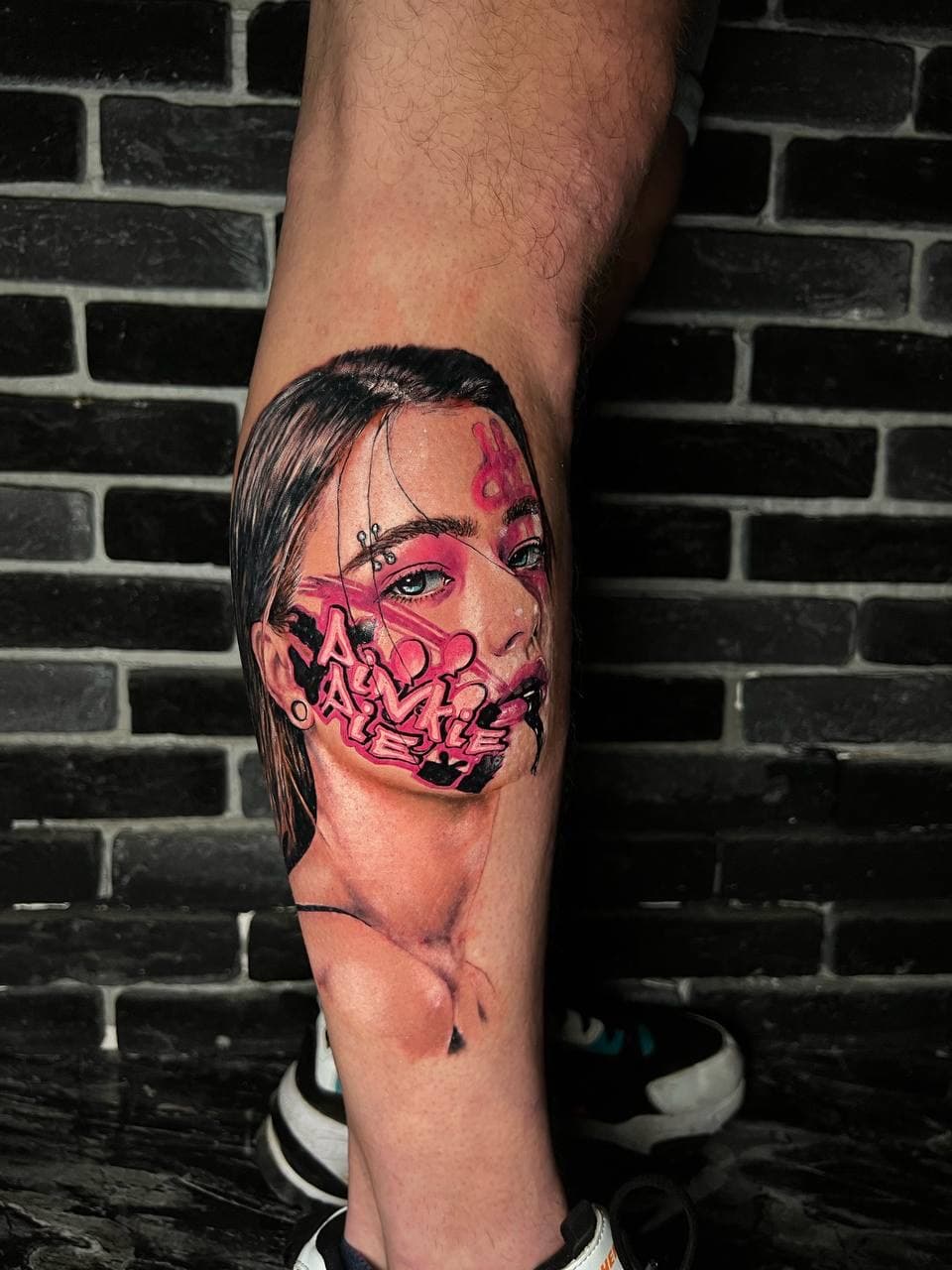 Color new-school portrait tattoo of a woman with pink graffiti lettering on a calf